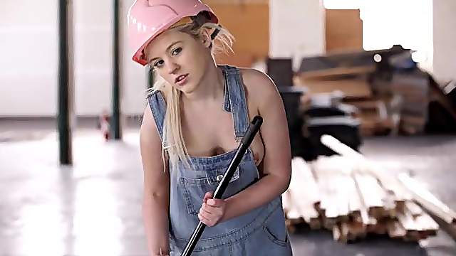 Young blonde sweeping a warehouse in her overalls